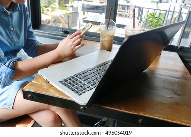 woman hand use phone and laptop multitasking working on laptop connecting wifi internet, businessman busy at office desk and finger typing on laptop computer sitting at wooden table