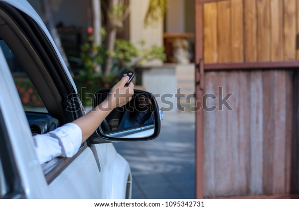 Woman hand using remote controller to open the\
automatic gate when arrived home, security and automatic system in\
concept.