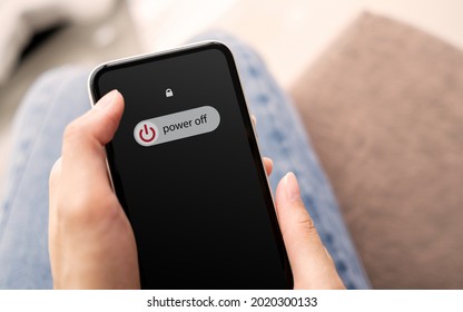 Woman hand using is sliding to turn off the mobile phone to reduce power consumption. Technology and environment concept  - Shutterstock ID 2020300133