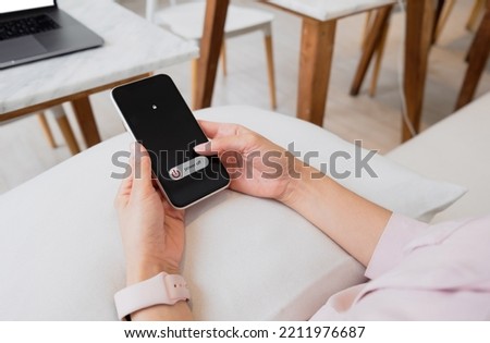 Woman hand using is sliding to turn off the mobile phone to reduce power consumption. Technology and environment concept 
