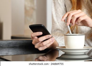 Woman hand using a smart phone during breakfast at home while is preparing a coffee cup