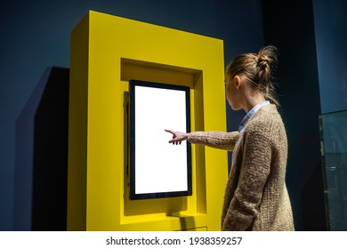 Woman hand using vertical white blank interactive touchscreen display of electronic multimedia kiosk in dark room - scrolling and touching. Mock up, copyspace, template and technology concept