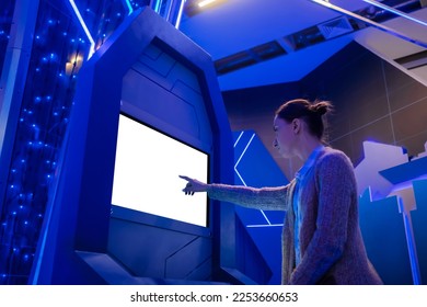 Woman hand using white blank interactive touchscreen display of electronic multimedia kiosk in dark room of scifi museum, exhibition: scroll, touch. Mock up, copyspace, template and technology concept - Shutterstock ID 2253660653