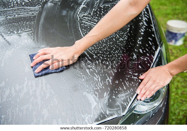 Woman\
hand washing a car with cloth and foam, car\
wash
