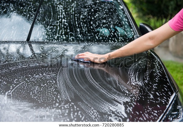 Woman\
hand washing a car with cloth and foam, car\
wash