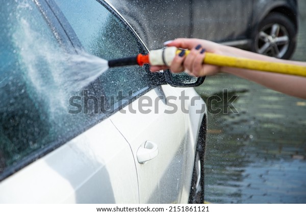 Woman hand washing car\
windshield. Car washing service background. High pressure car\
cleaning tool. 