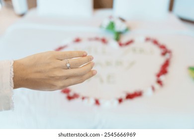 Woman hand wearing a diamond ring after say YES with message WILL YOU MARRY ME made of flower petals with bouquet on bed. Idea for marriage proposal, romantic surprise, wedding and engagement concept - Powered by Shutterstock