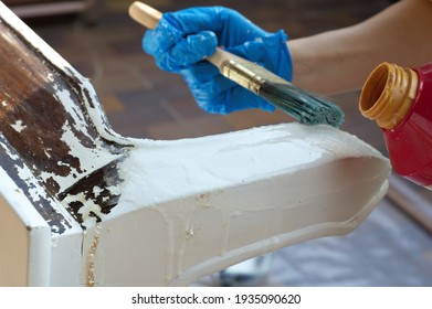 A Woman Hand Wearing A Working Glove And Holding A Brush Painting A Wooden Piece Of Furniture White And Brown In Home Outdoor