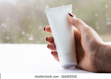 Woman Hand With White Cream Tube In A Bright Background