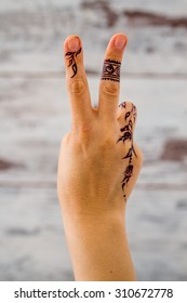 Woman hand without nail polish painted with floral figures using black henna