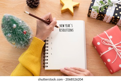 Woman Hand Writing New Year's Resolution On Note Paper In New Year Day.