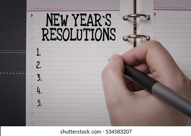 Woman Hand Writing New Year`s  Resolutions. New Year's Resolution Concept.