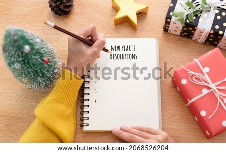 Woman hand writing New year's resolution on note paper in new year day.