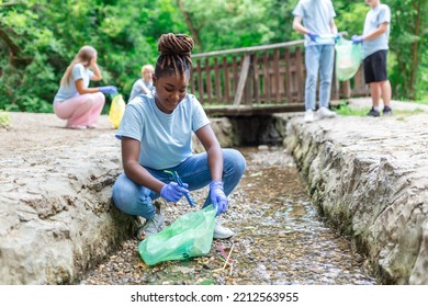 Woman handpicking gathering up garbage plastic straws garbage from the river at the park. World environment day.Environment concept.