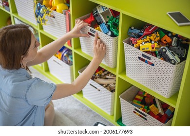 Woman Hands Applying Printing Sticker With Name Title Of Children Toys For Comfortable Sorting And Storage At Home. Caring Mother Organizing Domestic Space For Kids. Housekeeping And Household