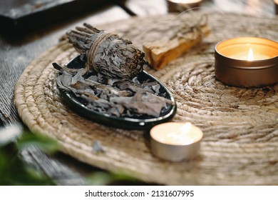 Woman Hands Burning White Sage, Before Ritual On The Table With Candles And Green Plants. Smoke Of Smudging Treats Pain And Stress, Clear Negative Energy And Meditation