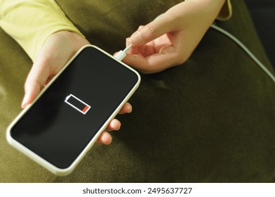 Woman hands Charging mobile phone battery with low battery. plugging a charger in a smart phone  with energy bank powerbank power charger Modern lifestyle energy technology concept