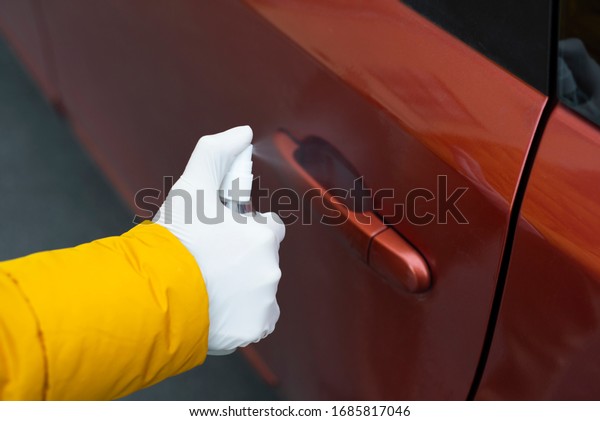 Woman hands close up disinfect a red car door\
handle with a hand sanitizer. Coronavirus pandemic spreading\
precautions measures\
concept.