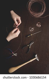 Woman Hands Close Up Making Wire Wrapped Jewelry Top View Preparation Process Dark. Female Girl Bend  Craft Handmade Copper  Wire Working Tools On The Table. Handicraft People Art Concept.