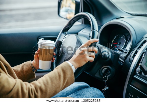 woman hands close up. driving car. view from\
inside. drinking coffee. road\
trip