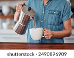 Woman, hands and coffee with moka pot for morning, caffeine or breakfast beverage in mug at home. Closeup of female person pouring latte, cappuccino or espresso for drink, energy or liquid in kitchen