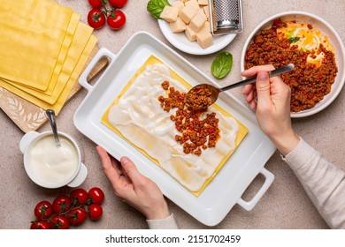 Woman Hands Cooking Lasagna.  Raw Italian Pasta And Ingredients, Lasagne Flat Sheets, Meat Sauce Or Ragu Bolognese, Ground Meats And Tomato Sauce, Parmesan Cheese, Bechamel Sauce. Top View.