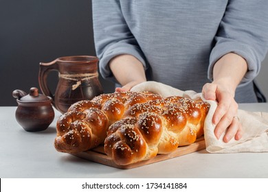 Woman hands covering the homemade Challah -  special bread in Jewish cuisine.Main ingredients are eggs, white flour, water, sugar, salt  and yeast. Decorated  with sesame and poppy seeds.