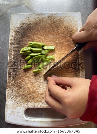 A woman hands of cutting petai or twisted cluster bean on the cutting board