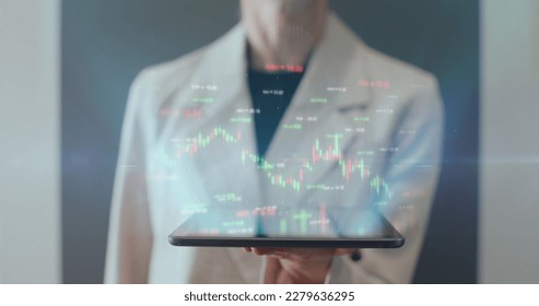 Woman hands with digital tablet pc computer and 3d hologram of futuristic finance stock exchange market chart. Bar graph with auto trading computer coding artificial intelligence technology, AI - Powered by Shutterstock