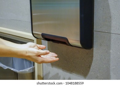 Woman Hands Dries Wet Hand In Modern Vertical Hand Dryer In Public Restroom WC