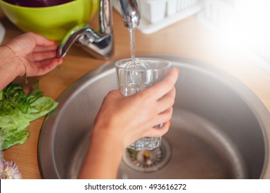 Woman hand's filling the glass of water. - Shutterstock ID 493616272
