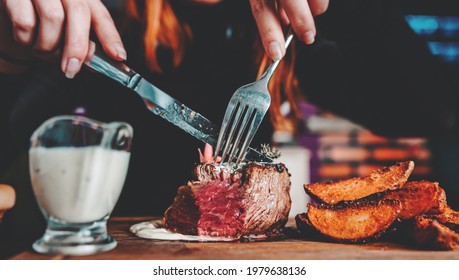 Frau mit Gabel und Messer, die Rindfleisch-Steak im Café essen