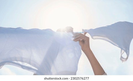 Woman hands hangs laundry on clothesline - Powered by Shutterstock