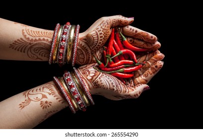 Woman hands with henna holding red chili isolated on black background with clipping path 