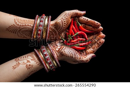 Woman hands with henna holding red chili isolated on black background with clipping path 