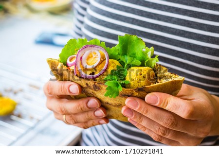 Woman hands hold baked chickpea falafel to eat with hummus, salad leaves and pita bread. Vegan healthy food. 