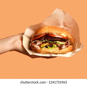 Woman hands hold big cheeseburger barbeque sandwich with marble beef on purple background