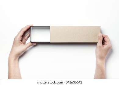 A Woman Hands Hold A Brown Empty(blank, Hollow, Vacant) Long Paper Box(case, Package) And Open On The White Desk(table) Top View Isolated White At The Studio.