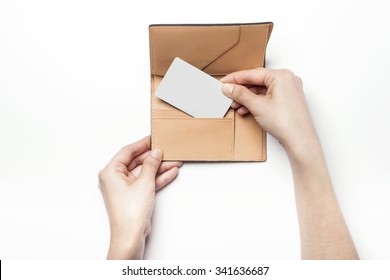 A Woman Hands Hold A Brown Leather Wallet(case, Pocket) For Passport With A White Credit Card On The White Desk(table) Top View Isolated White At The Studio.