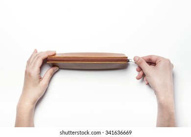 A Woman Hands Hold A Empty(blank, Hollow, Vacant) Brown Leather Pencil Case And Zipper On The White Desk(table) Top View Isolated White At The Studio.