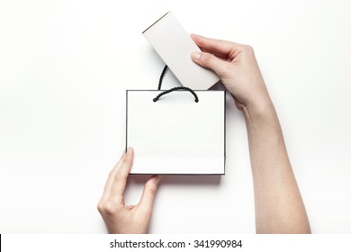 A Woman Hands Hold A Empty(blank, Vacant, Hollow) White Paper Bag And Box For Cosmetics, Accessory, Top View Isolated White At The Studio.