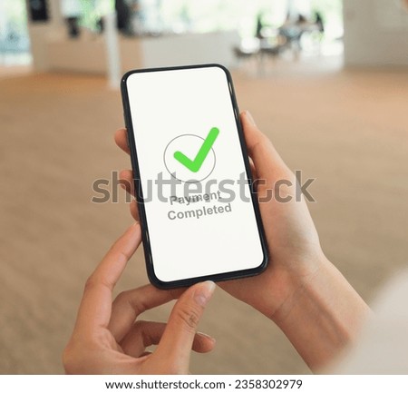 Woman hands hold smartphone and showing payment completed message on mobile.