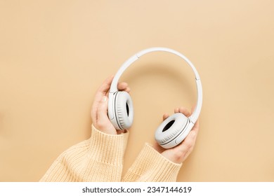 Woman hands hold wireless headphones top view. Learning and education concept, listening audio books, music or online courses, studying or home office work, cozy fall concept, copy space - Powered by Shutterstock