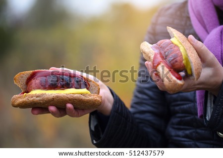Woman hands holding barbecue grilled hot dog with yellow mustard and  ketchup