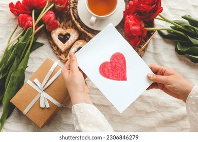 Woman hands holding a beautiful hand drawn Mother's Day greeting card with red envelope, I Love You Mom message on the card. - Powered by Shutterstock