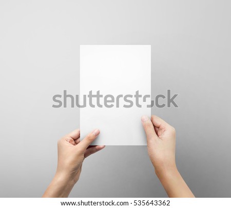 Woman hands holding blank paper sheet A5 size or letter paper on grey background.