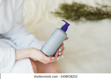 Woman Hands Holding Bottle With Lotion Or Shampoo In The Bathroom.