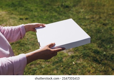 Woman Hands Holding A Box With Pizza On Nature Background. Fast Pizza Delivery. Mock Up. Fast Food Banner, Summer Time