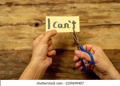 Woman hands holding card with written text i can't do it cutting the letter T with scissors so you read I can in Success and Challenge concept Believe in yourself and Motivation to achieve results.