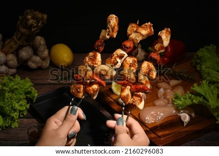 Woman hands holding delicious grilled chicken skewers with tomato, sweet pepper and onions